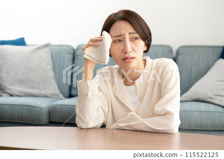 Middle-aged woman wiping sweat, menopause 115522125
