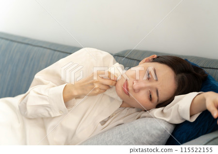 Middle-aged woman wiping sweat, menopause, lying down Middle-aged woman wiping sweat, menopause, lying down 115522155