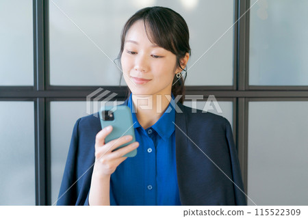 A smiling woman in her twenties holding a smartphone A smiling woman in her twenties holding a smartphone 115522309