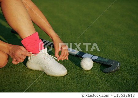 girl hockey player tying sneakers on the field hockey field, concept of playing field hockey girl hockey player tying sneakers on the field hockey field, concept of playing field hockey 115522618