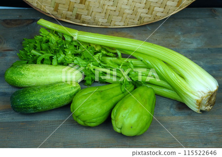 a bunch of green cucumbers, chayote and celery on a wooden table. a bunch of green cucumbers, chayote and celery on a wooden table. 115522646