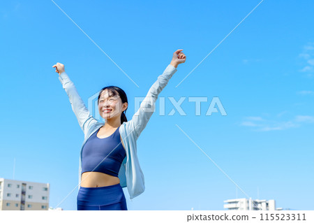 A young woman pumping her fist in the blue sky, diet, city, liberation, front, cropped 115523311