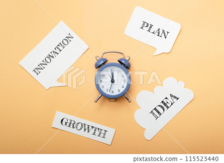 A clock sits on a table with a bunch of paper with words like growth, plan 115523440