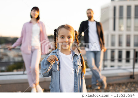 Happy family on rooftop with daughter holding key Happy family on rooftop with daughter holding key 115523584