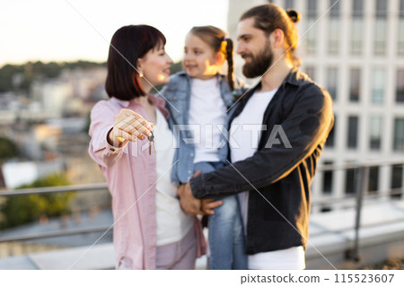 Happy family holding keys to their new home on rooftop Happy family holding keys to their new home on rooftop 115523607