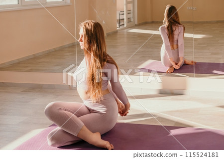 Young sporty woman, fitness instructor in pink sportswear doing stretching and pilates on yoga mat in the studio with mirror. Female fitness yoga routine concept. Healthy lifestyle and harmony. Young sporty woman, fitness instructor in pink sportswear doing stretching and pilates on yoga mat in the studio with mirror. Female fitness yoga routine concept. Healthy lifestyle and harmony. 115524181