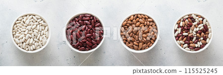 Ceramic bowls with red and white and variegated and mixed raw dry beans on kitchen table. 115525245