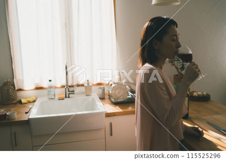 Housewife drinking wine in the kitchen Housewife drinking wine in the kitchen 115525296