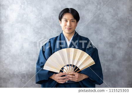 A man in traditional Japanese clothing holding a folding fan A man in traditional Japanese clothing holding a folding fan 115525303