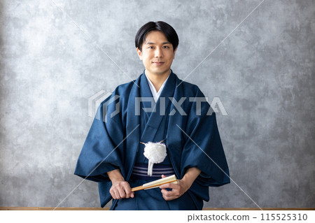 A man in traditional Japanese clothing holding a folding fan 115525310