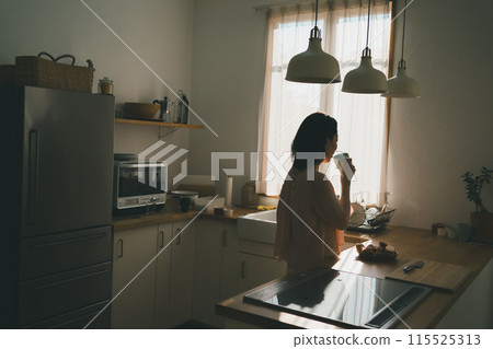 一位 40 多歲的家庭主婦在廚房裡拿著杯子 115525313