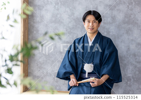 A man in traditional Japanese clothing holding a folding fan A man in traditional Japanese clothing holding a folding fan 115525314
