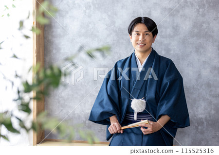 A man in traditional Japanese clothing holding a folding fan 115525316