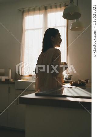 一位 40 多歲的家庭主婦在廚房裡拿著杯子 115525323