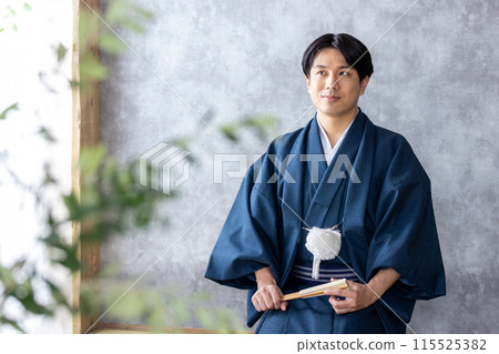 A man in traditional Japanese clothing holding a folding fan A man in traditional Japanese clothing holding a folding fan 115525382