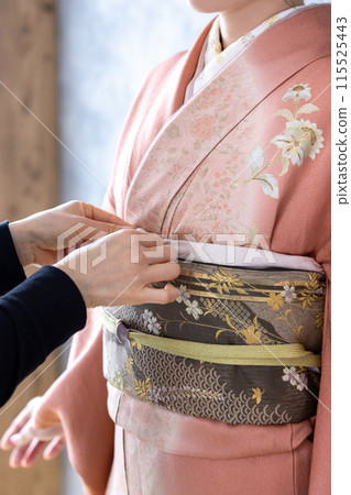 A woman in a kimono getting dressed A woman in a kimono getting dressed 115525443