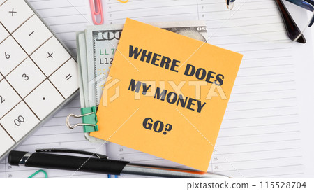 words Where does my money go. Business concept on a yellow sticker next to American hundred dollar bills, a calculator, a pen on a white background 115528704