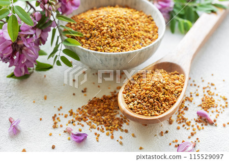 Healthy bee pollen grains. Bee pollen on a bowl and acacia flowers. Healthy bee pollen grains. Bee pollen on a bowl and acacia flowers. 115529097