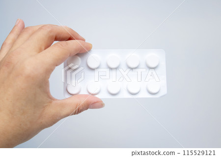 A person holding a blister pack of pills with a hand gesture A person holding a blister pack of pills with a hand gesture 115529121