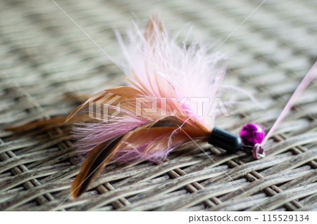 A cat toy with pink feathers and a pink bell, suitable for felines to play with 115529134