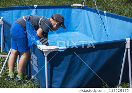 Boy actively involved in removing impurities from a pool, ensuring the water remains pure and reflective 115529575