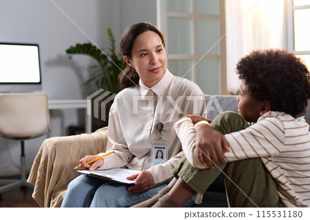 Portrait of female psychologist talking to young child in therapy session for mental health support, copy space 115531180