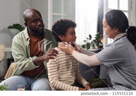 Side view portrait of friendly smiling nurse examining African American boy during at home visit copy space Side view portrait of friendly smiling nurse examining African American boy during at home visit copy space 115531210