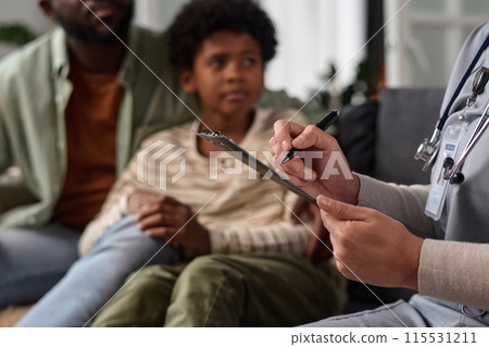 Close up of unrecognizable nurse holding clipboard while consulting African American family copy space Close up of unrecognizable nurse holding clipboard while consulting African American family copy space 115531211