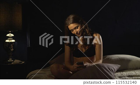 Girl looking at mobile phone in the dimmed bedroom 115532140