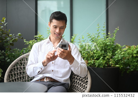 Handsome businessman sitting outside of office snd using mobile phone. Communication and technology concept Handsome businessman sitting outside of office snd using mobile phone. Communication and technology concept 115532432