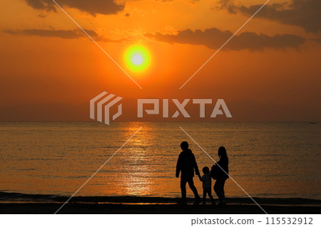 黃昏時分，一家人沿著逗子海灘的海灘散步的剪影變成橘色 115532912