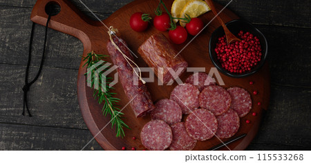 切板上的陳年薩拉米香腸,配上粉紅胡椒、迷迭香、櫻桃番茄和檸檬 切板上的陳年薩拉米香腸,配上粉紅胡椒、迷迭香、櫻桃番茄和檸檬 115533268