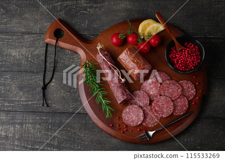 切板上的陳年薩拉米香腸，配上粉紅胡椒、迷迭香、櫻桃番茄和檸檬 115533269