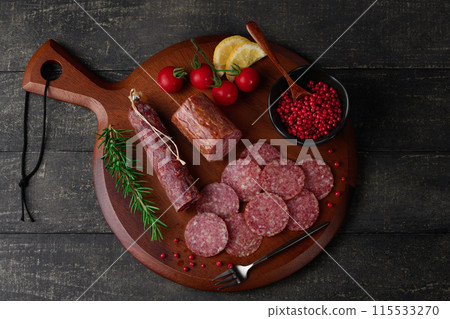 切板上的陳年薩拉米香腸，配上粉紅胡椒、迷迭香、櫻桃番茄和檸檬 115533270
