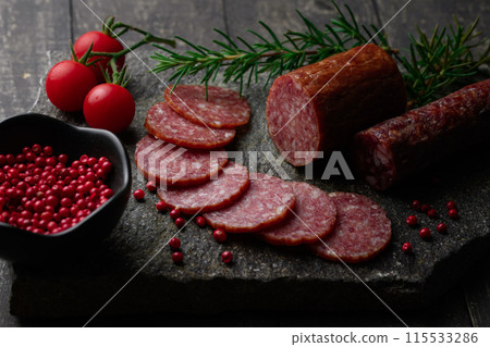 切板上的陳年薩拉米香腸,配上粉紅胡椒、迷迭香、櫻桃番茄和檸檬 切板上的陳年薩拉米香腸,配上粉紅胡椒、迷迭香、櫻桃番茄和檸檬 115533286