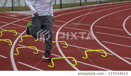 High school boy running over yellow mini hurdles 115534013