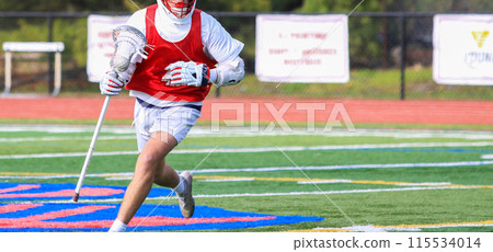 Lacrosse player running with a short stick carrying the ball during a game 115534014