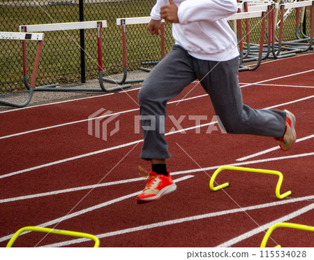 Runner running over yellow mini hurdles in practice Runner running over yellow mini hurdles in practice 115534028