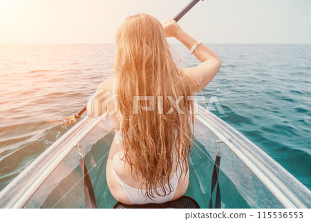 Woman in kayak back view. Happy young woman with long hair floating in transparent kayak on the crystal clear sea. Summer holiday vacation and cheerful female people relaxing having fun on the boat 115536553