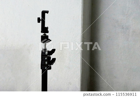Modern tripod with smartphone holder on white wall 115536911