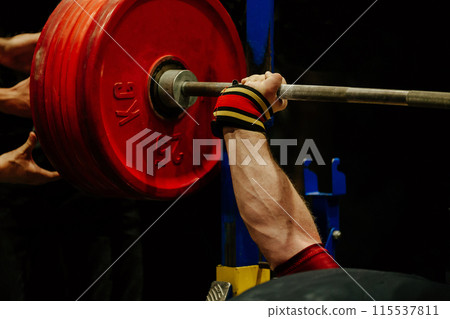 athlete arm in wristband holds barbell in bench press athlete arm in wristband holds barbell in bench press 115537811