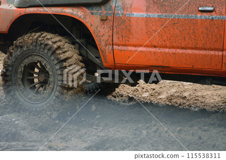 a red SUV in the mud accelerates to overcome obstacles. Off-road competition for SUVs. a red SUV in the mud accelerates to overcome obstacles. Off-road competition for SUVs. 115538311
