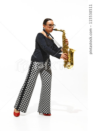 Full-length portrait of elegant senior woman, saxophonist in checkered pants performs intensely isolated on white background 115538511