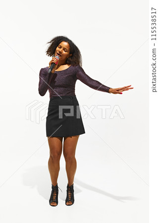 Vocalist in a glittery outfit and stylish boots delivers a passionate performance, singing isolated on white background 115538517