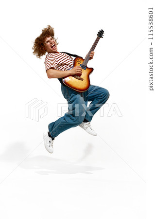 Young man, guitarist in striped shirt and denim jeans passionately playing electric guitar isolated on white background 115538601