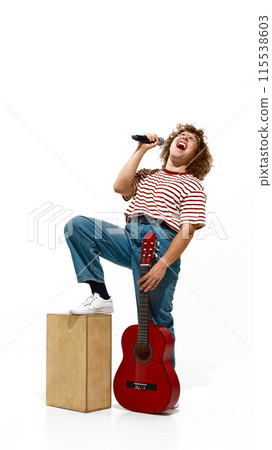 Full-length portrait of emotional young man, musician in jeans and striped shirt, staying with guitar an singing isolated on white background 115538603