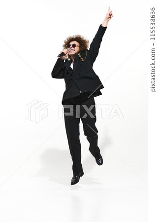 Powerful vocal performance. Musician, man in a dark suit, emotionally singing in microphone isolated on white background 115538636