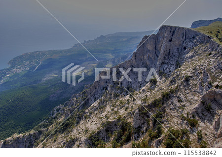 Mount Ai-petri.View from above. View from the mountain, below is a valley flowing into the Black Sea, shadows of clouds are reflected on it. Mount Ai-petri.View from above. View from the mountain, below is a valley flowing into the Black Sea, shadows of clouds are reflected on it. 115538842