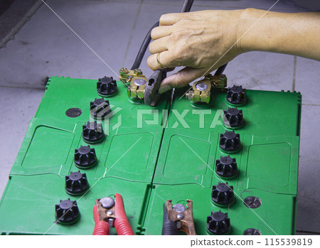 electrician connecting battery terminals 115539819