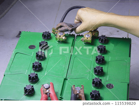 electrician connecting battery terminals electrician connecting battery terminals 115539820